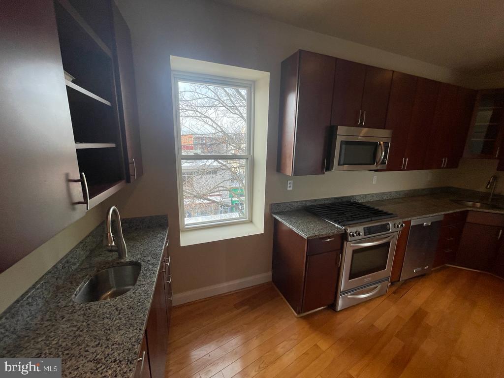 1033 Park Road Northwest, Unit 6 Washington, DC 20010 - Photo 6 of 38 a kitchen with granite countertop a stove and a wooden floor