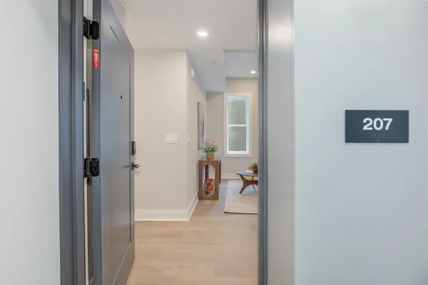 a view of a hallway with wooden floor and a living room