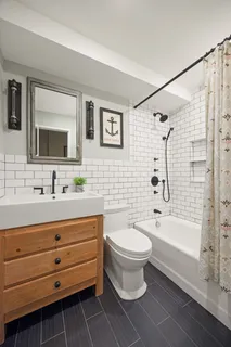 a bathroom with a sink a toilet a mirror a bathtub and shower