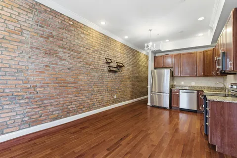 a view of kitchen with stainless steel appliances wooden floor and cabinets