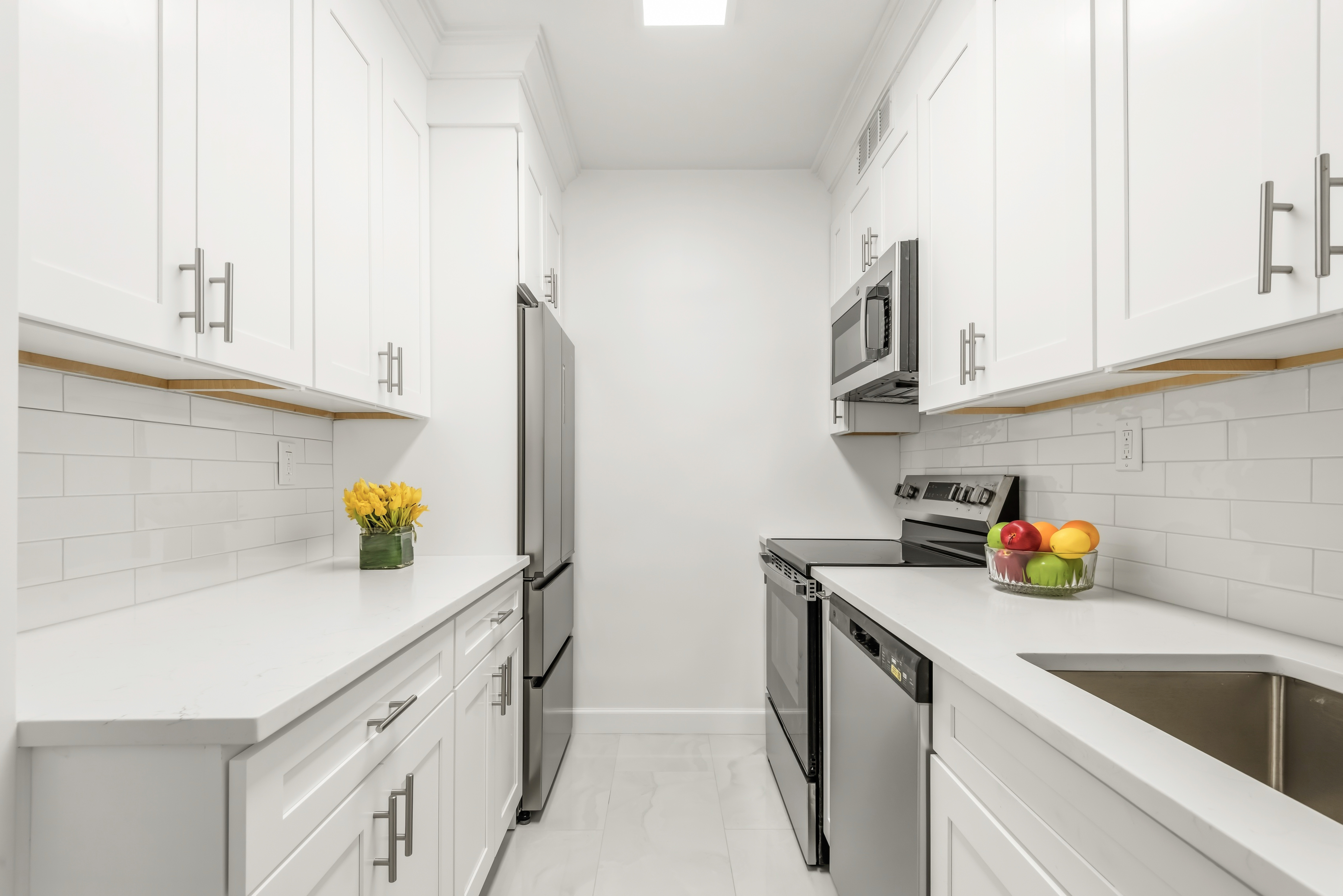 175 East 62nd Street, Unit 14B Manhattan, NY 10065 - Photo 9 of 12 a kitchen with stainless steel appliances a sink a refrigerator and cabinets