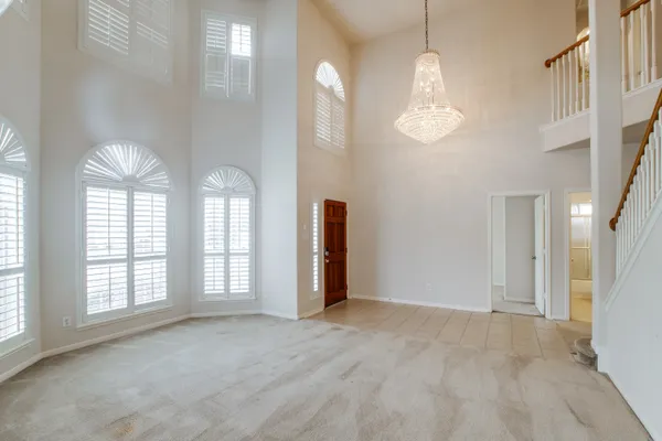 an empty room with chandelier and windows