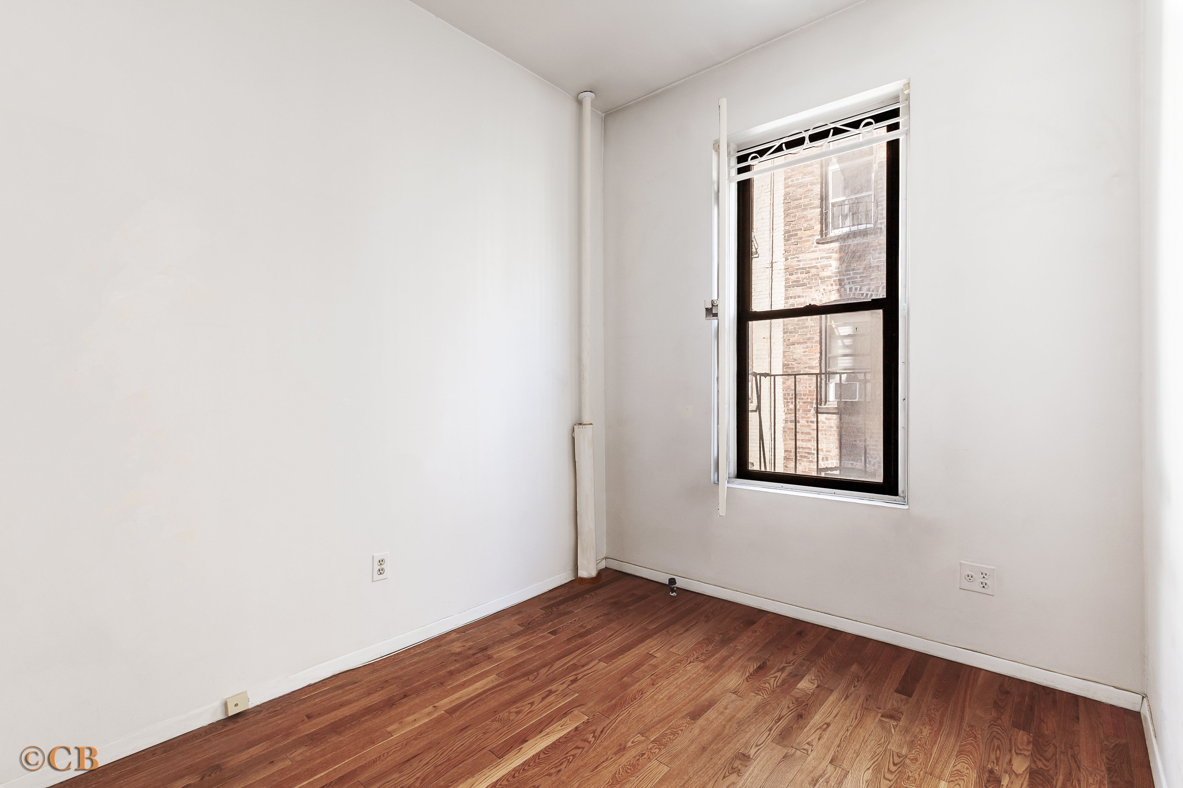 131 Thompson Street, Unit 4C Manhattan, NY 10012 - Photo 6 of 9 an empty room with wooden floor and windows