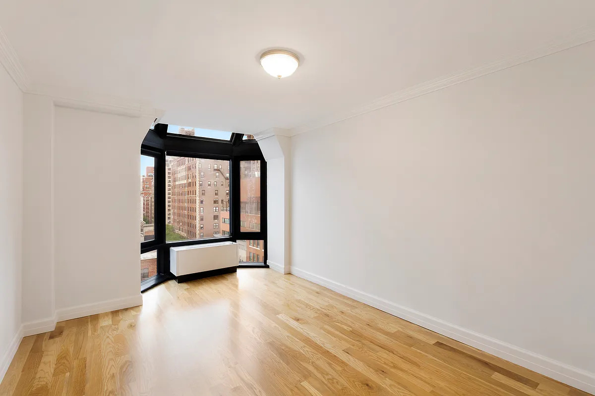 150 East 85th Street, Unit 11E Manhattan, NY 10028 - Photo 4 of 6 a view of an empty room with wooden floor and a window