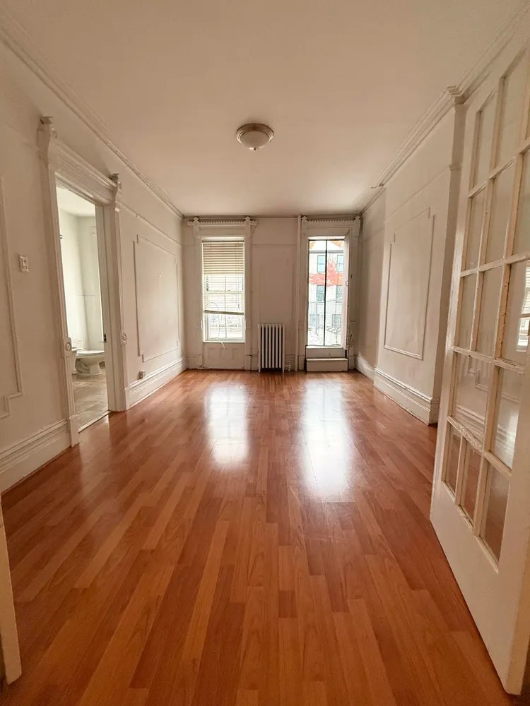 an empty room with wooden floor and windows
