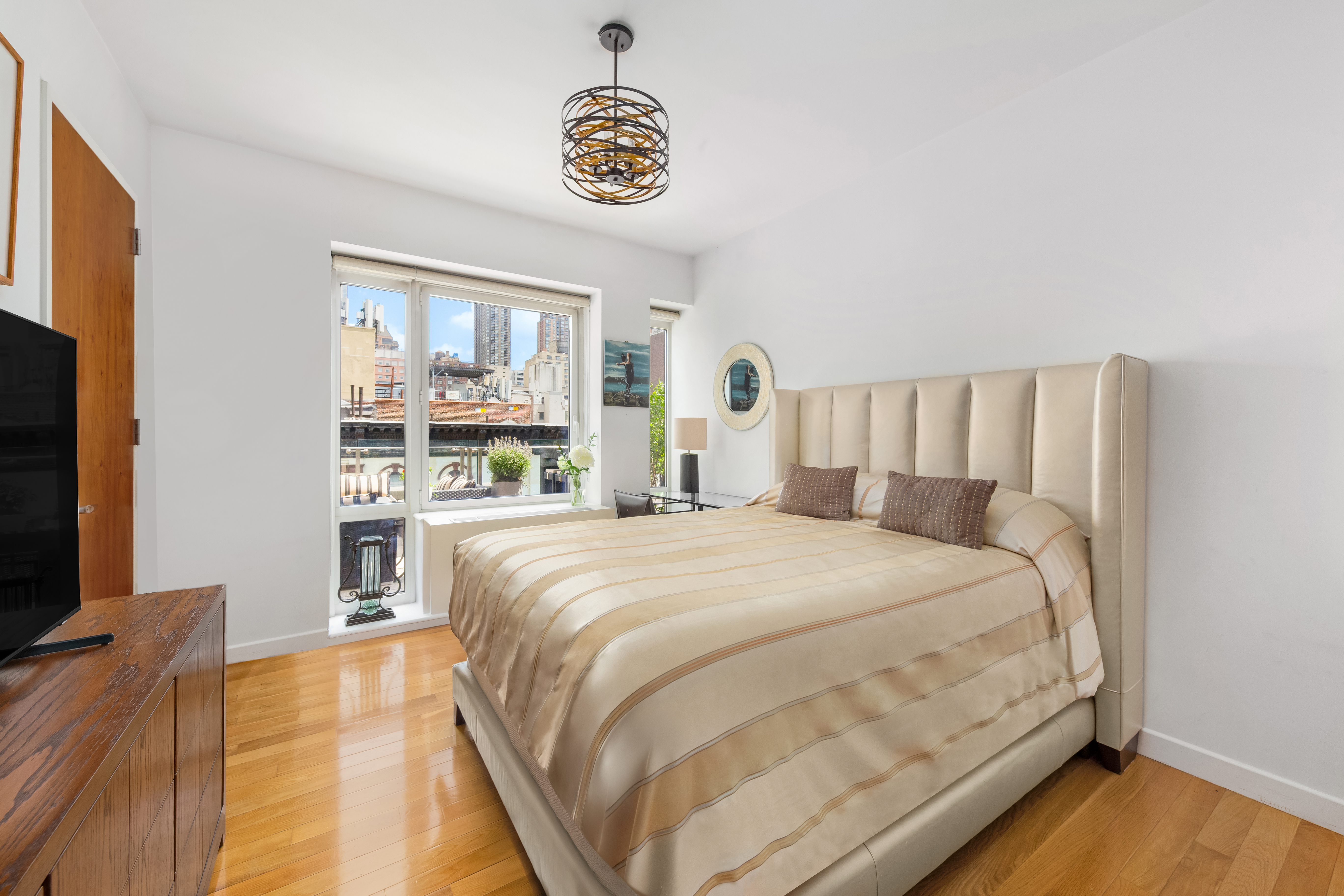 454 West 54th Street, Unit 7B Manhattan, NY 10019 - Photo 9 of 15 a large bed sitting in a bedroom next to a window with balcony