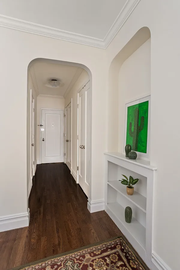 a view of a hallway to a livingroom with wooden floor and a window