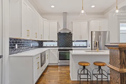 a kitchen with stainless steel appliances granite countertop a stove and white cabinets