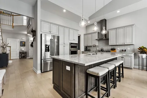 a kitchen with stainless steel appliances granite countertop a table chairs refrigerator and a sink