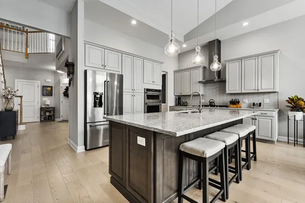 a kitchen with stainless steel appliances granite countertop a table chairs refrigerator and a sink