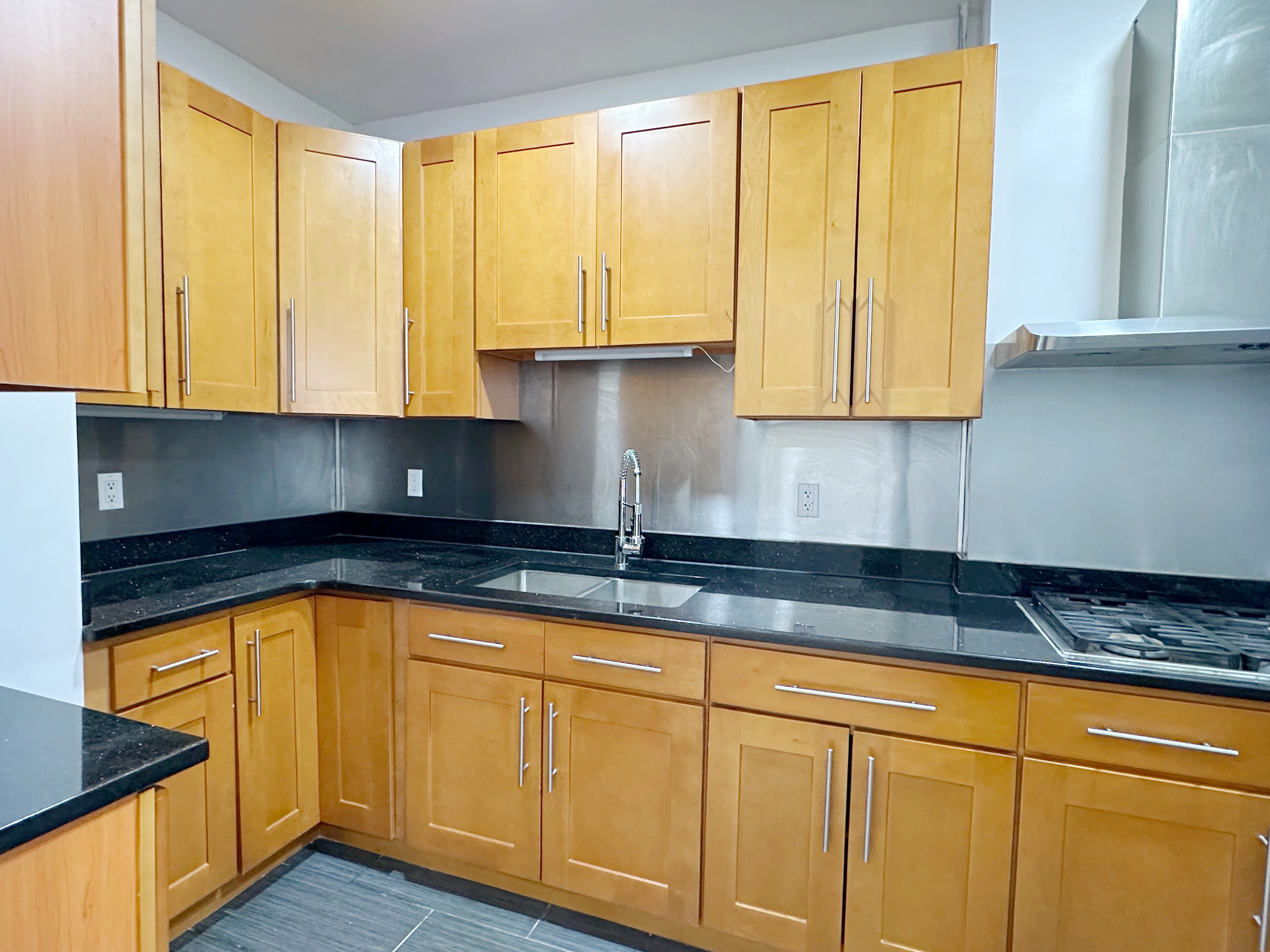 17-22 Menahan Street, Unit 1 Queens, NY 11385 - Photo 6 of 9 a kitchen with granite countertop cabinets and white appliances