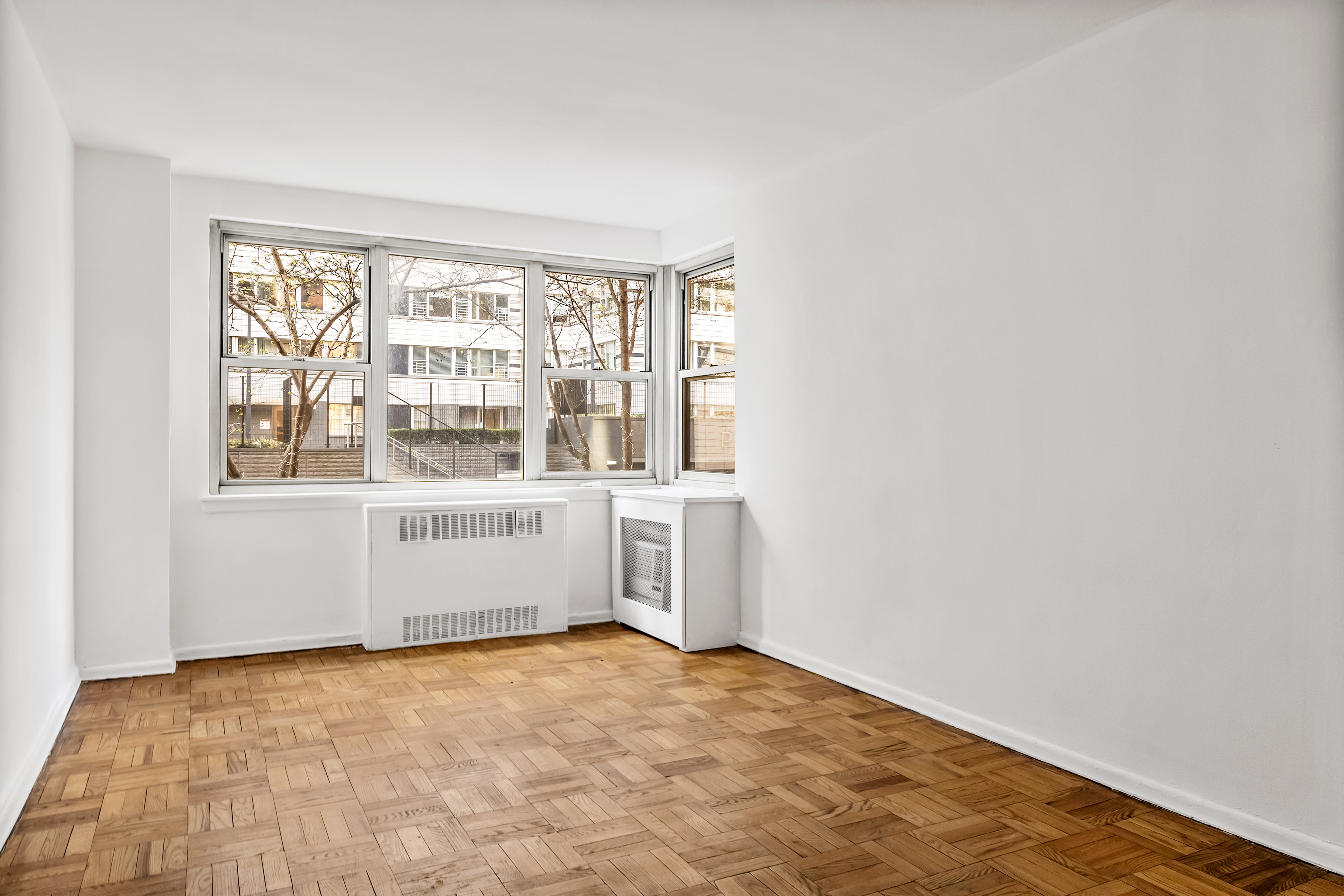 233 East 69th Street, Unit 2C Manhattan, NY 10021 - Photo 6 of 10 wooden floor in an empty room with a window
