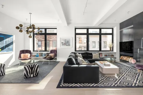 a living room with furniture floor to ceiling window and a flat screen tv