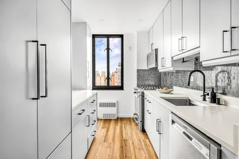 a kitchen with white cabinets and sink