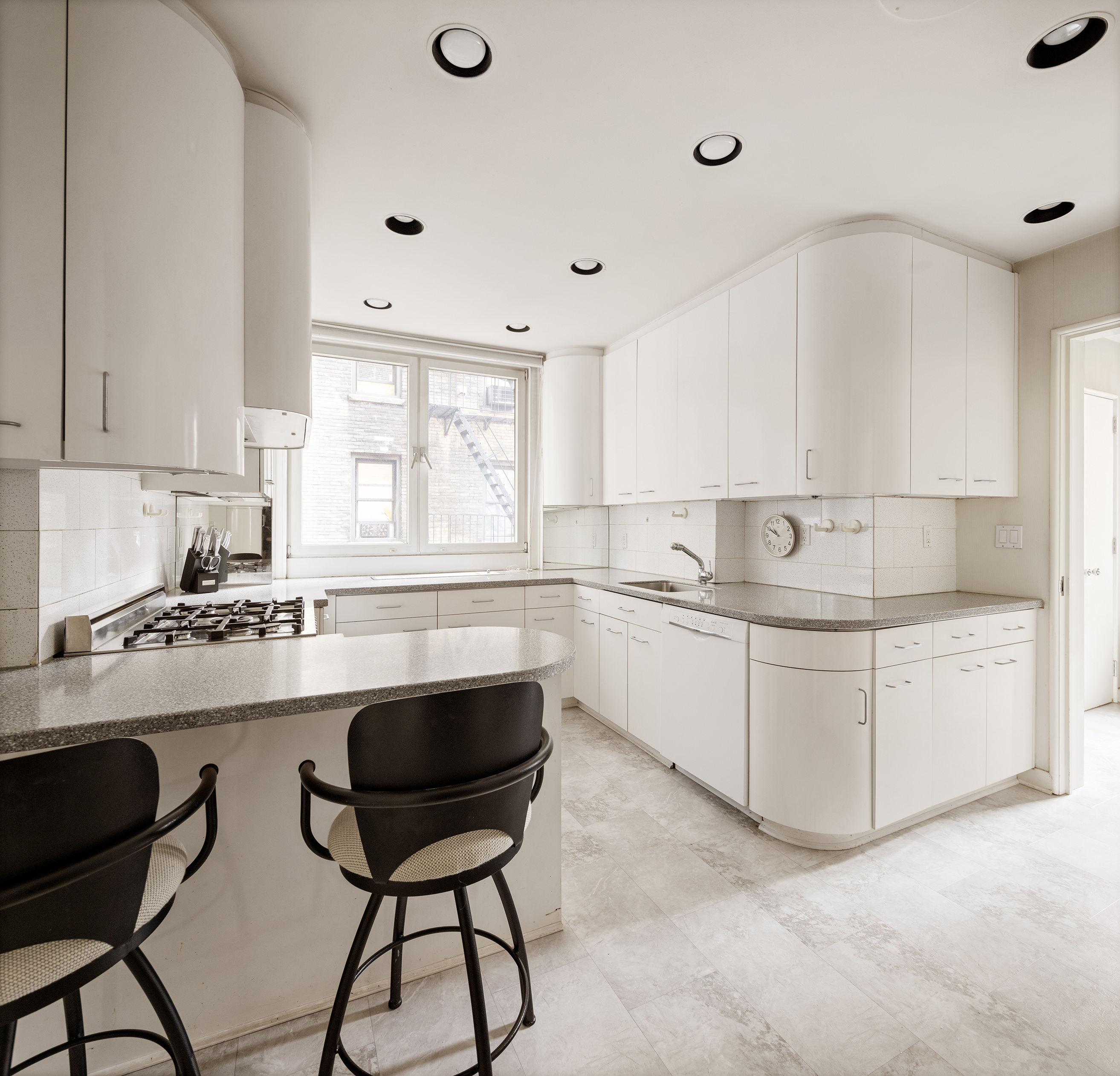 130 East 75th Street, Unit 4D Manhattan, NY 10021 - Photo 12 of 19 a kitchen with a stove a sink and white cabinets