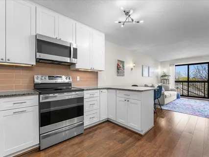 a kitchen with granite countertop white cabinets stainless steel appliances and wooden floor