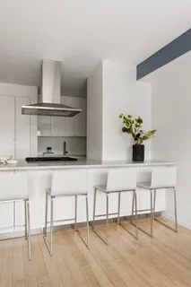 a white kitchen with a stove and white cabinets with wooden floor
