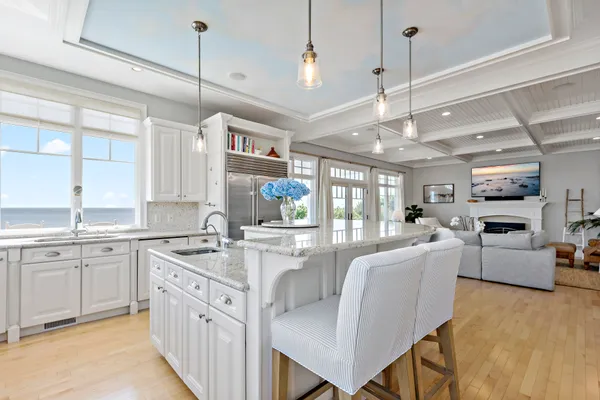 a large white kitchen with cabinets a sink dishwasher a stove and a dining table with wooden floor
