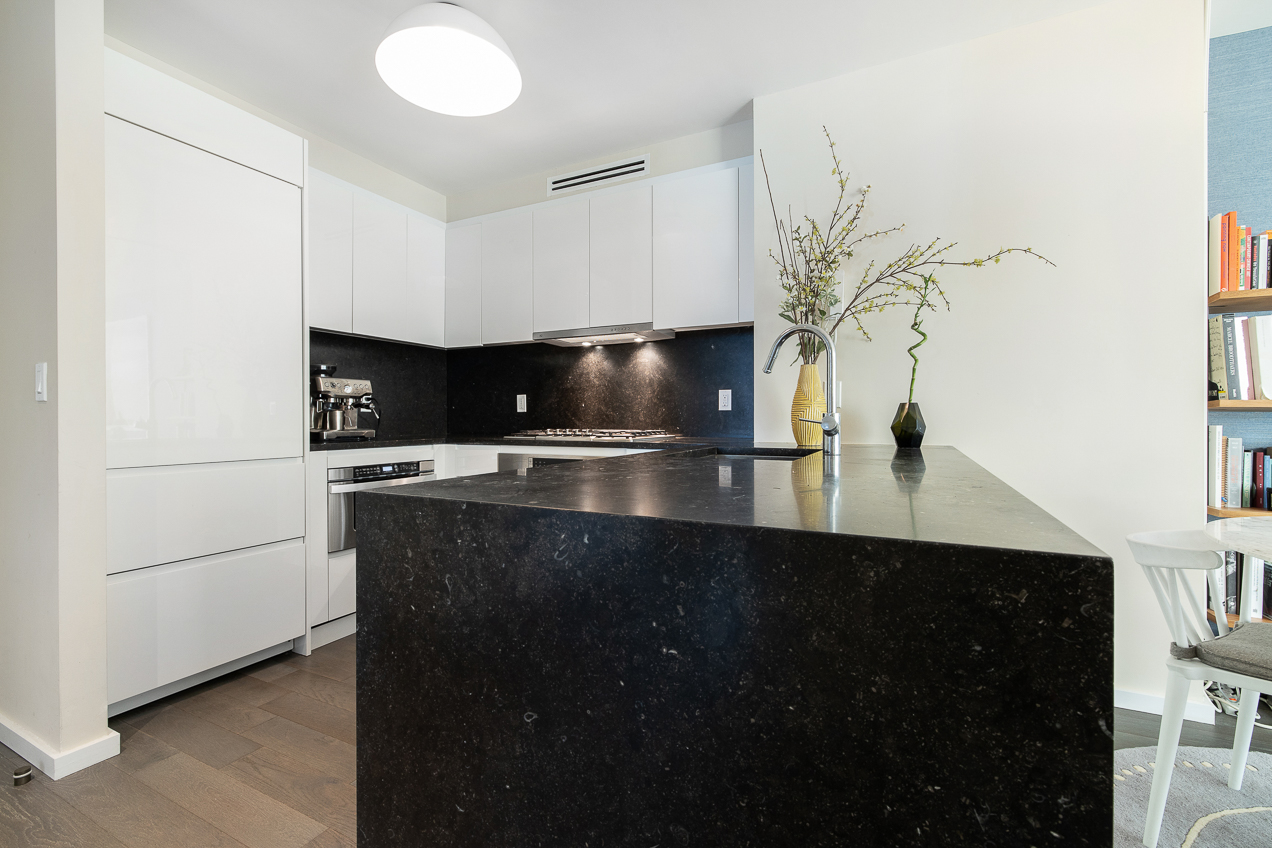 385 1st Avenue, Unit 6G Manhattan, NY 10010 - Photo 5 of 19 a kitchen with kitchen island a sink stainless steel appliances and cabinets