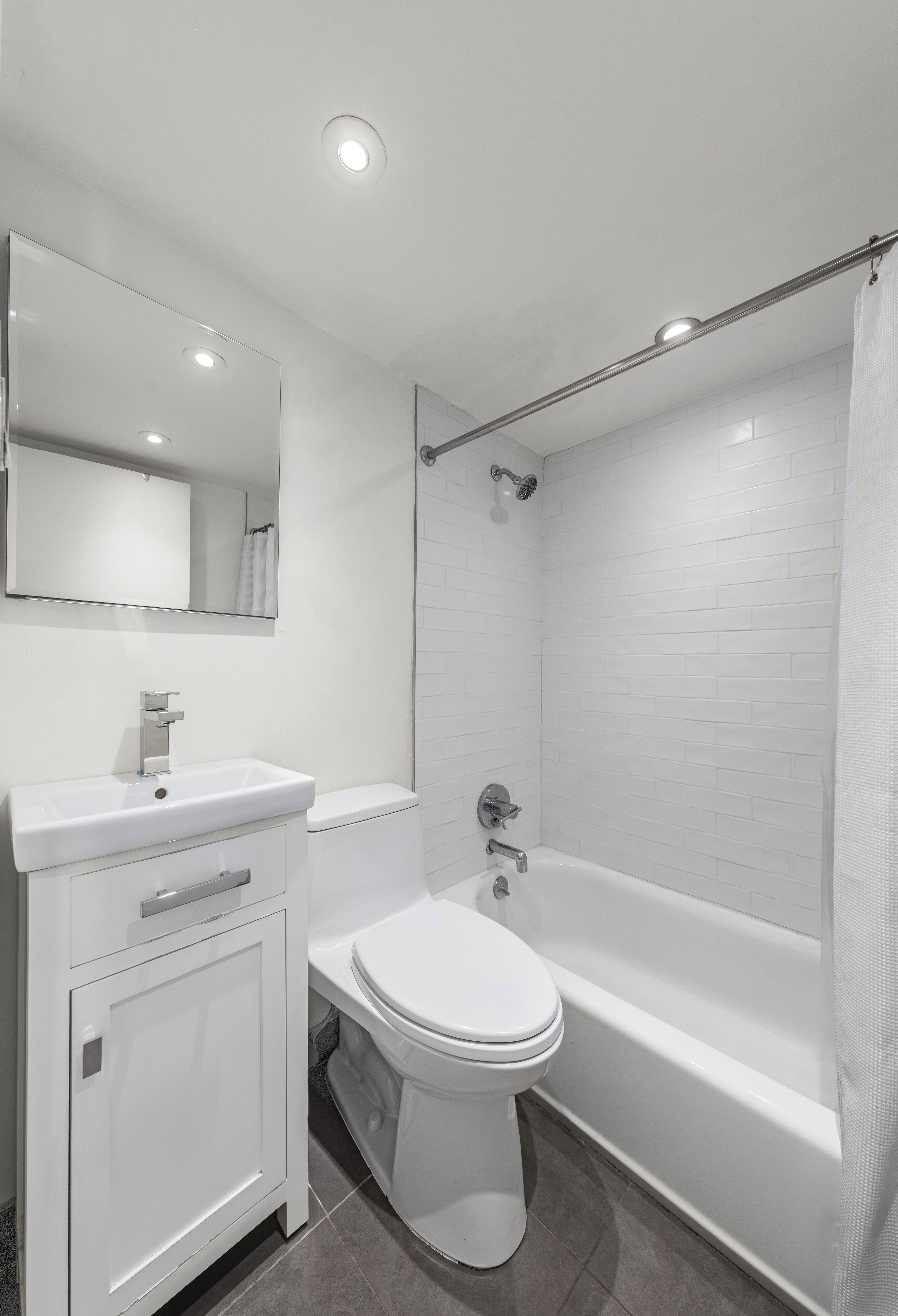 184 Thompson Street, Unit 4E Manhattan, NY 10012 - Photo 7 of 10 a bathroom with a toilet sink vanity tub and shower