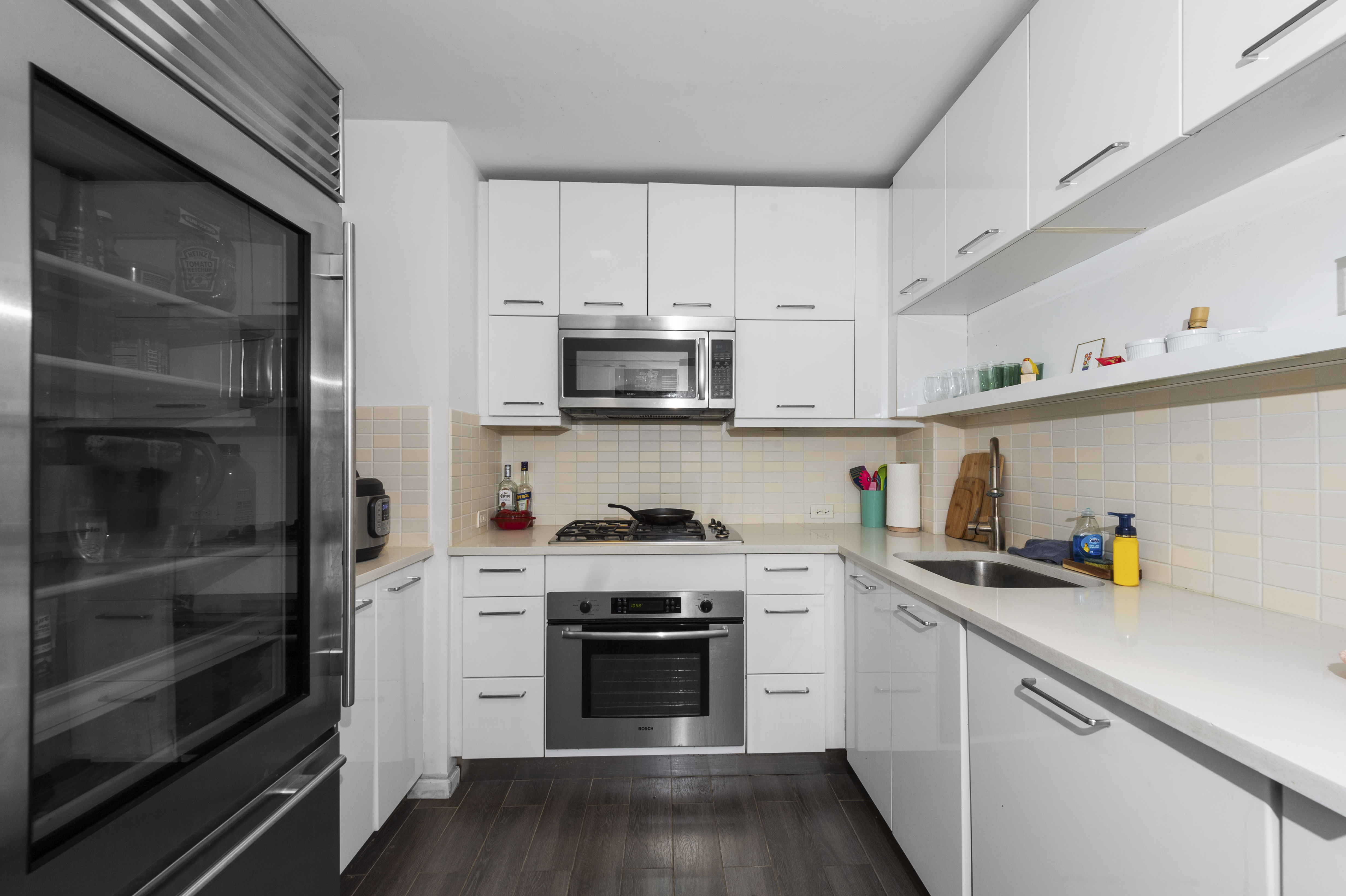 635 West 42nd Street, Unit 14K Manhattan, NY 10036 - Photo 12 of 19 a kitchen with cabinets stainless steel appliances and wooden floor