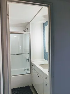 a bathroom with a tub shower vanity and a sink