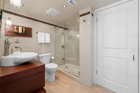 a bathroom with a shower sink vanity mirror and toilet