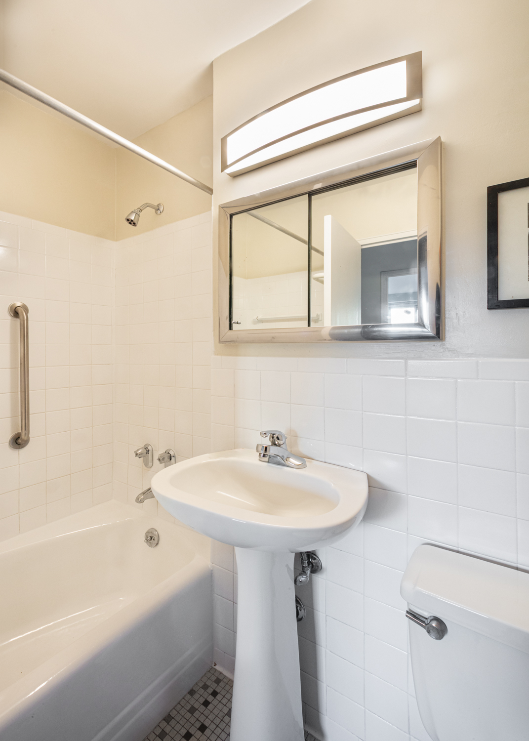 401 East 86th Street, Unit 5M Manhattan, NY 10028 - Photo 4 of 8 a bathroom with a sink a mirror and a bathtub