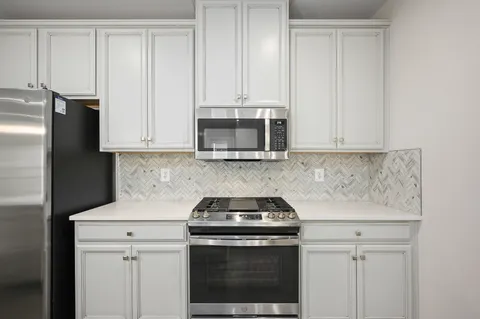 a kitchen with granite countertop white cabinets and stainless steel appliances