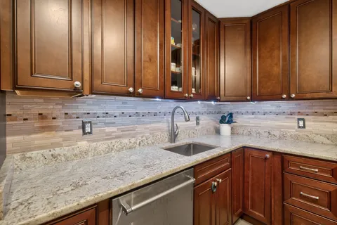 a kitchen with granite countertop a sink a stove and cabinets
