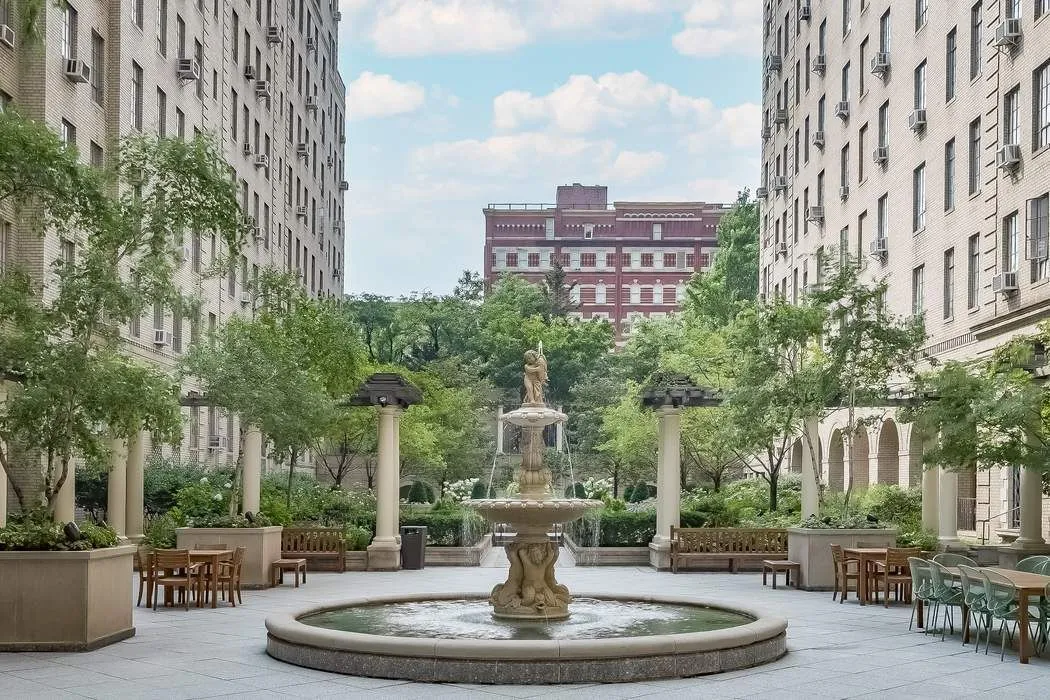 a building exterior with water fountain and trees
