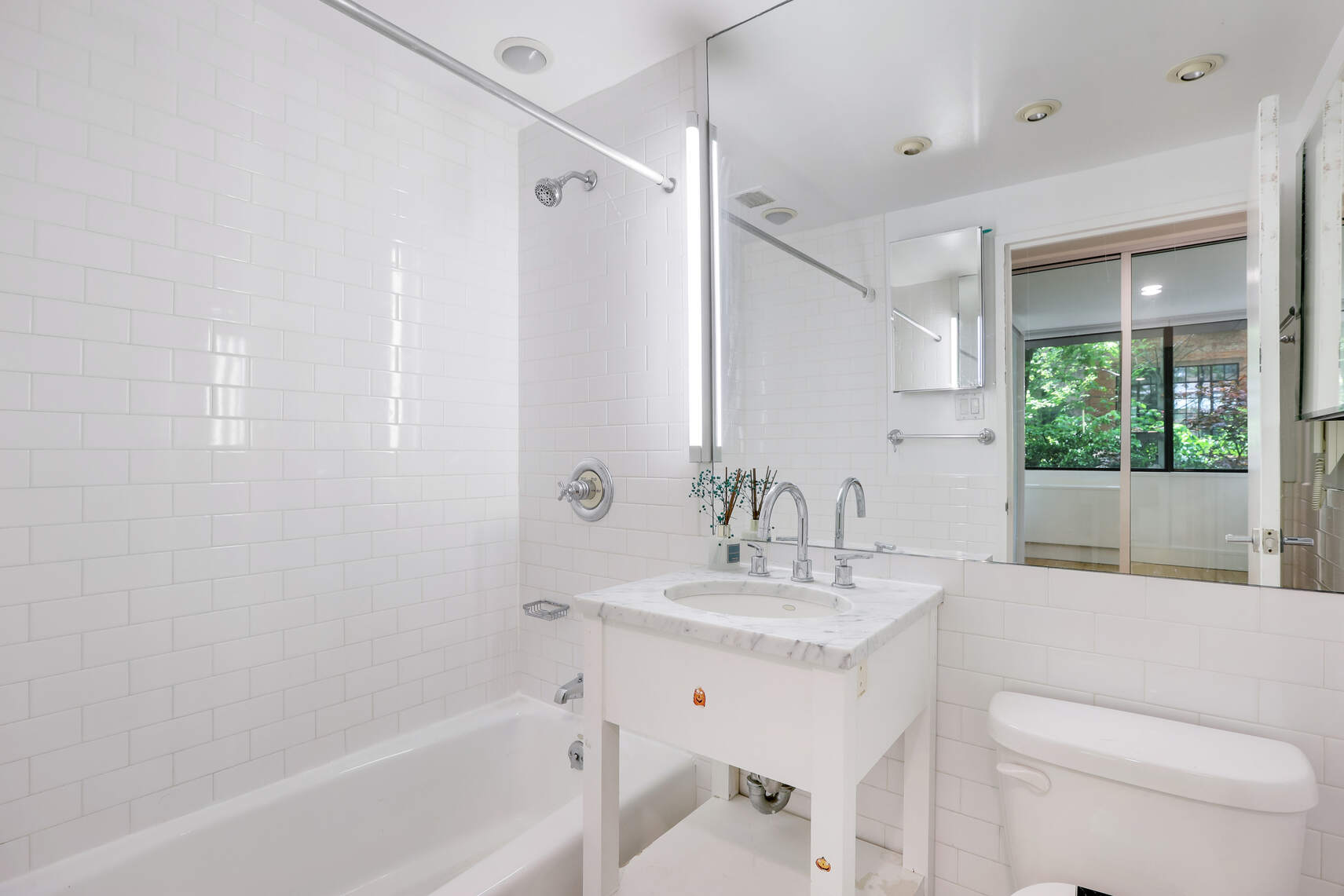 344 West 23rd Street, Unit 1E Manhattan, NY 10011 - Photo 11 of 19 a bathroom with a bathtub shower sink vanity mirror and toilet