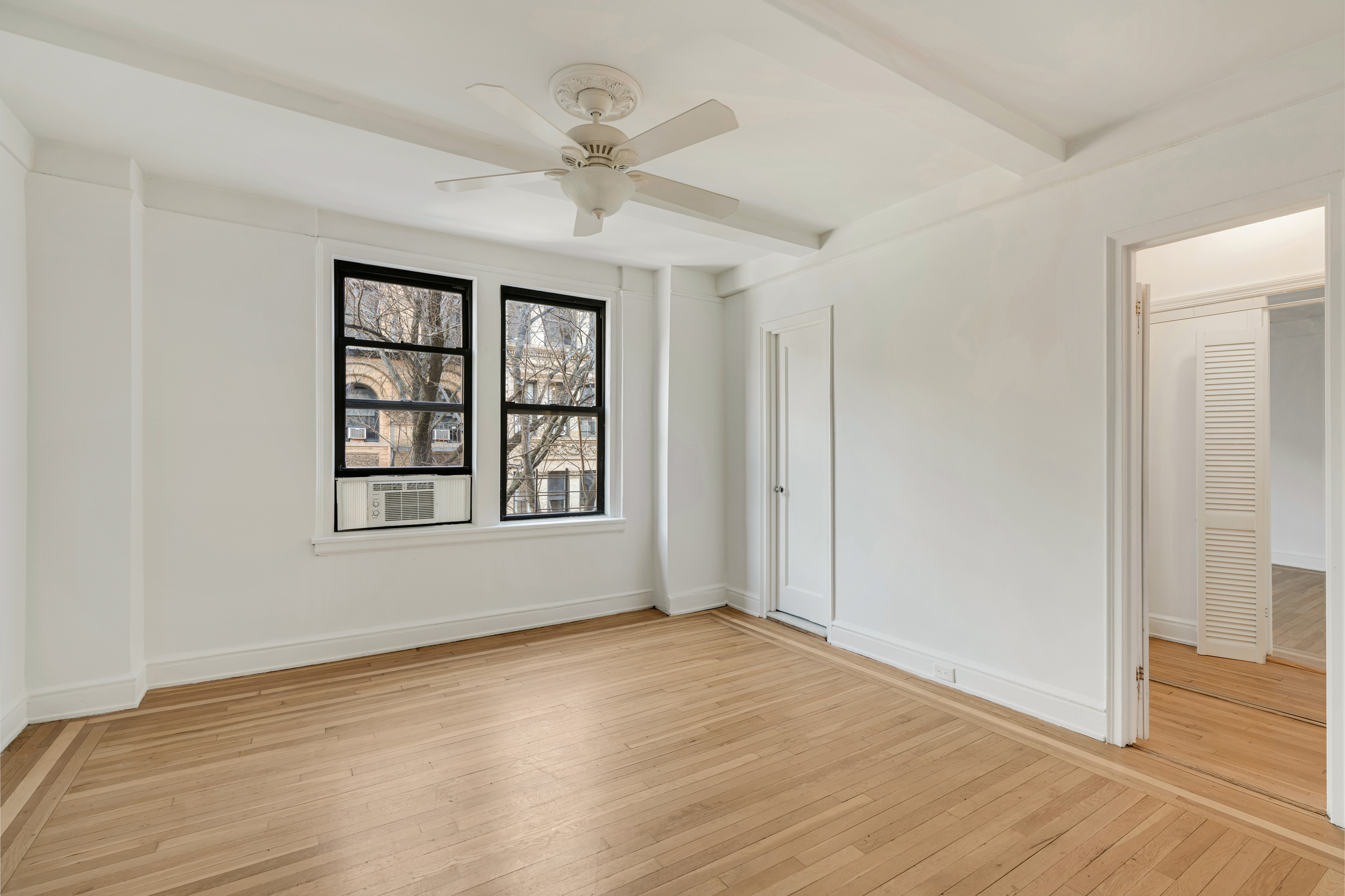 74 West 68th Street, Unit 5A Manhattan, NY 10023 - Photo 19 of 25 an empty room with wooden floor chandelier fan and windows