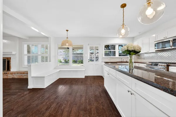 a view of a kitchen with kitchen island a stove a wooden floor and a large window