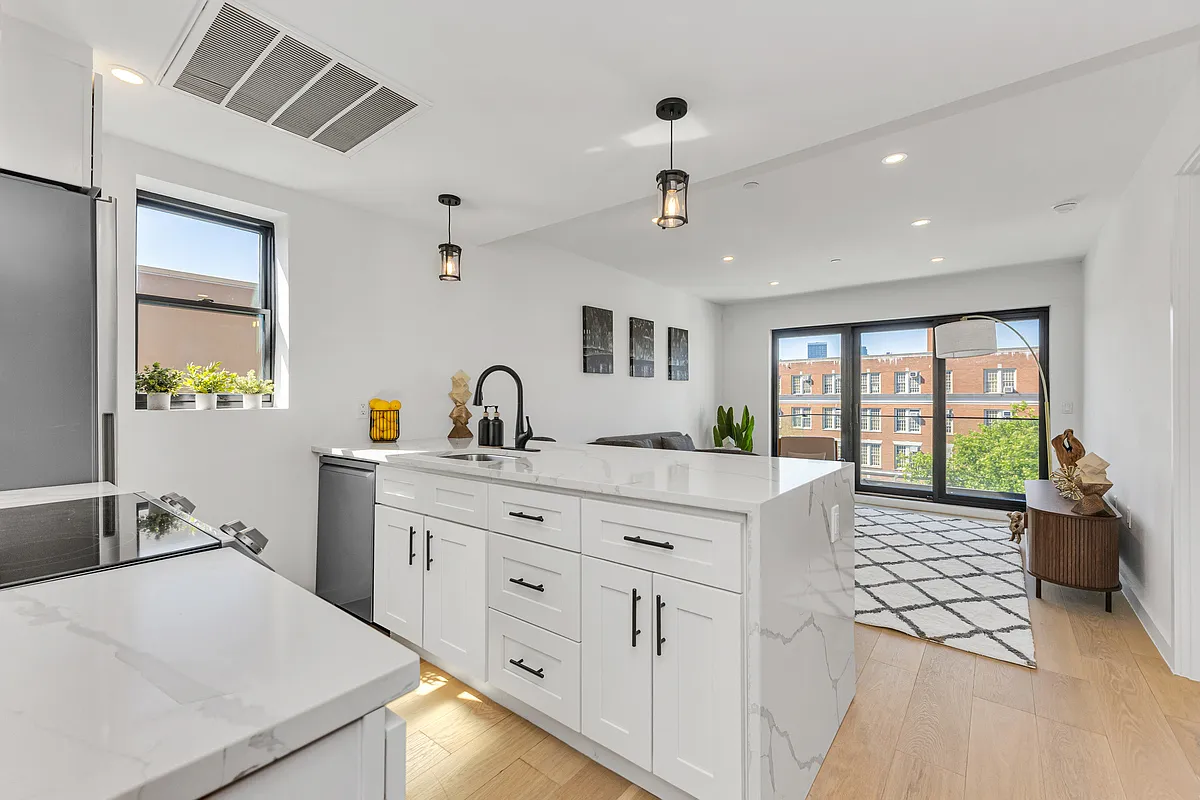 21-10 31st Avenue, Unit 6R Queens, NY 11106 - Photo 2 of 17 a large white kitchen with a stove a sink a chimney and a dining table with garden view
