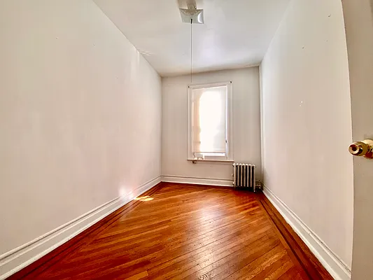 6825 7th Avenue, Unit 2 Brooklyn, NY 11220 - Photo 6 of 9 a view of an empty room with wooden floor and a window