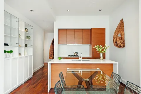 a dining room with stainless steel appliances furniture a rug and a kitchen view