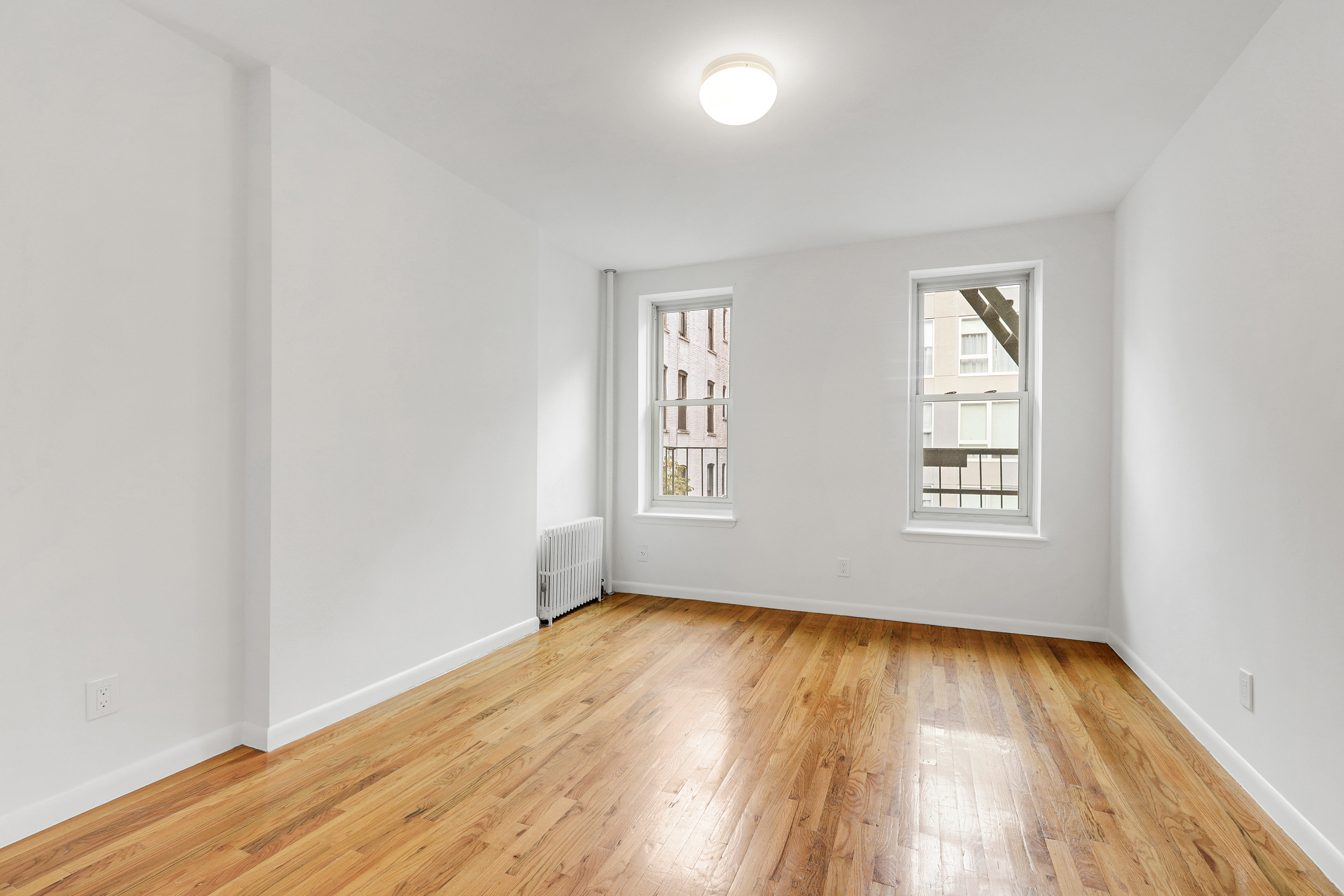 323 West 43rd Street, Unit 4R Manhattan, NY 10036 - Photo 6 of 14 an empty room with wooden floor and windows