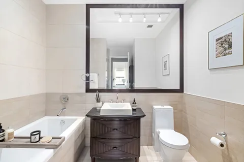 a bathroom with a bathtub sink mirror vanity and toilet