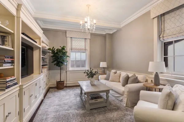 a living room with furniture a chandelier and a flat screen tv