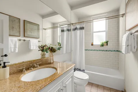 a bathroom with a granite countertop sink toilet a mirror a bathtub and shower