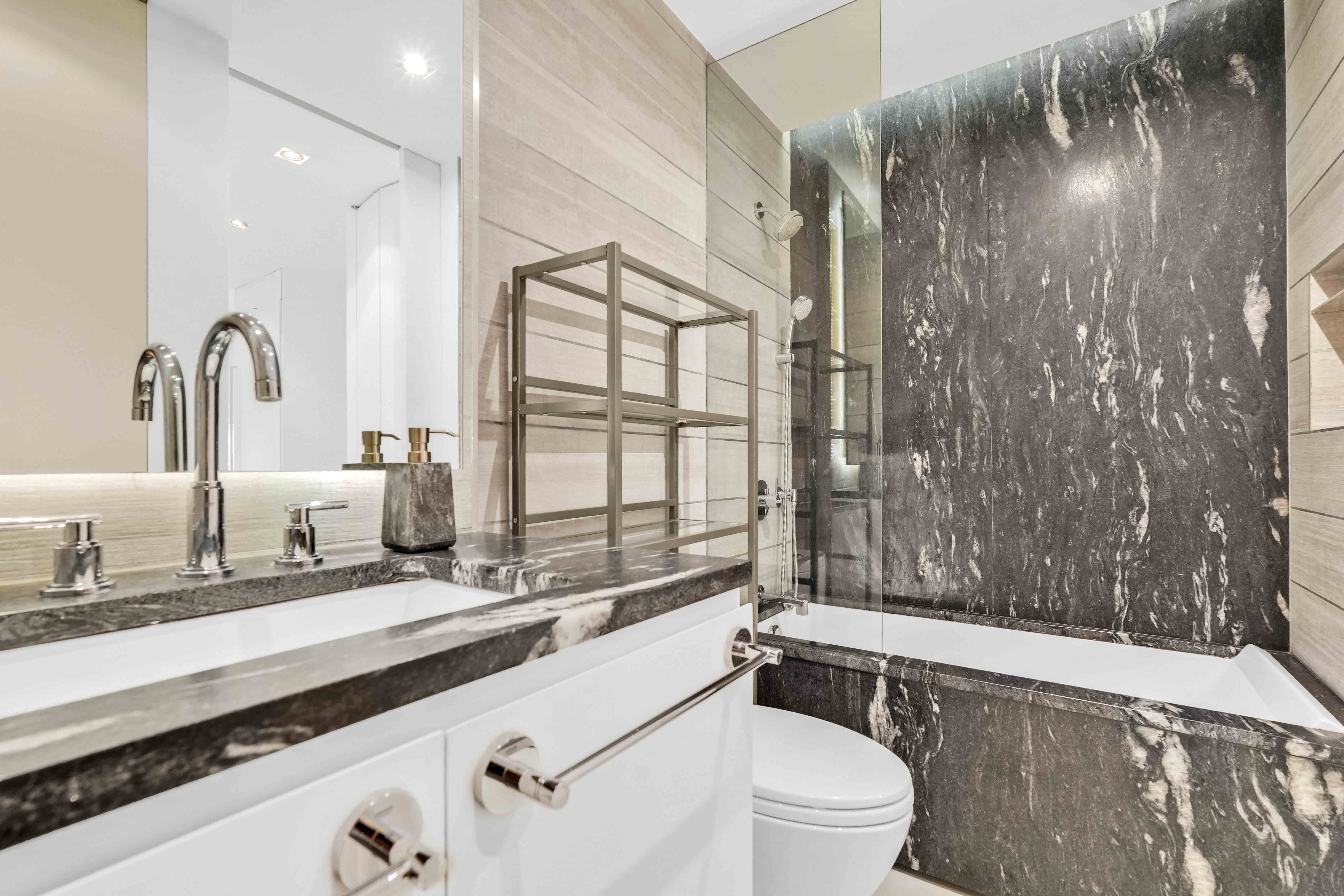 117 East 57th Street, Unit 20F Manhattan, NY 10022 - Photo 12 of 18 a bathroom with a sink a toilet a mirror and shower