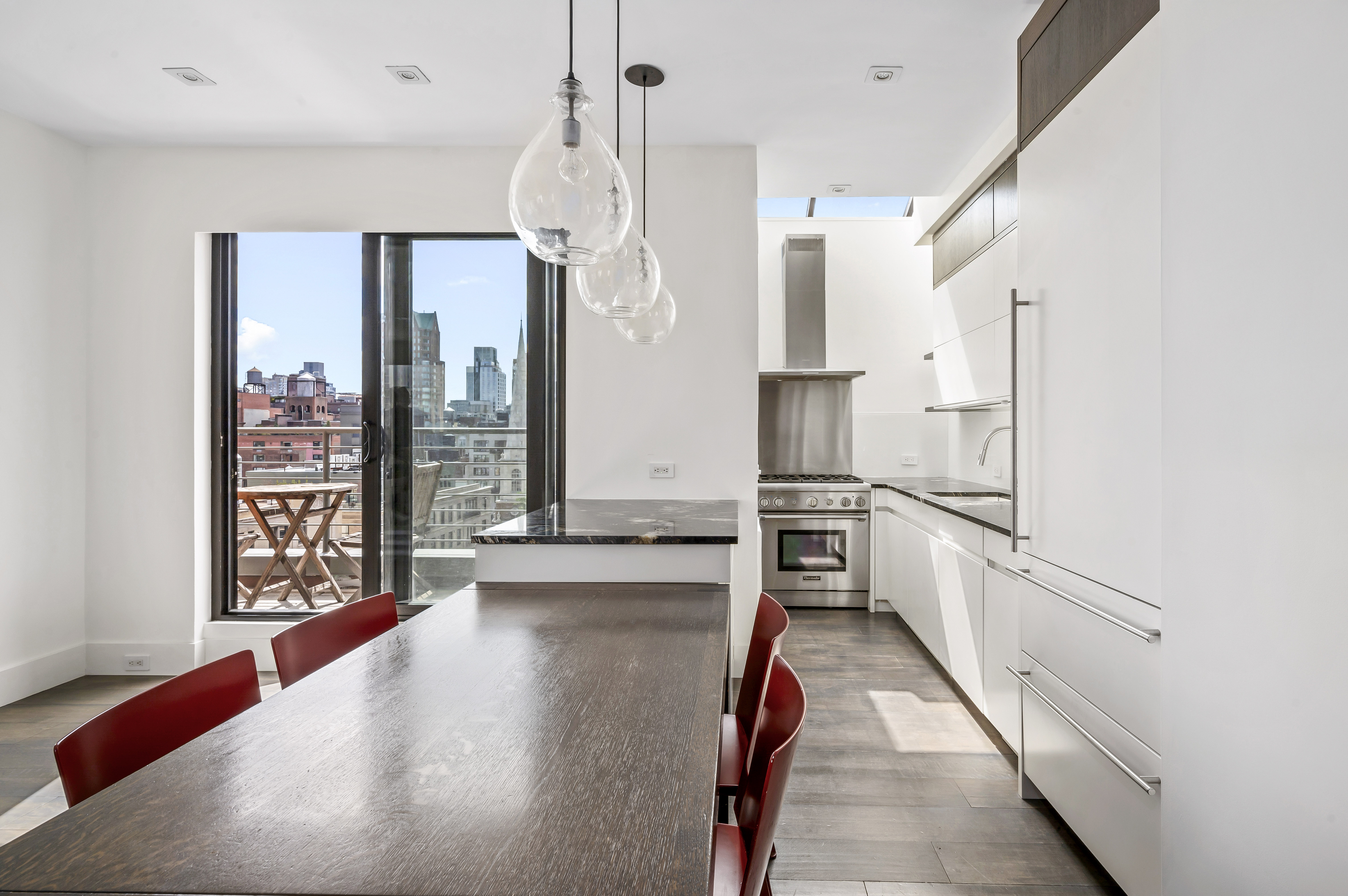 131 East 81st Street, Unit PH15 Manhattan, NY 10028 - Photo 6 of 11 a kitchen with stainless steel appliances refrigerator oven table and chairs