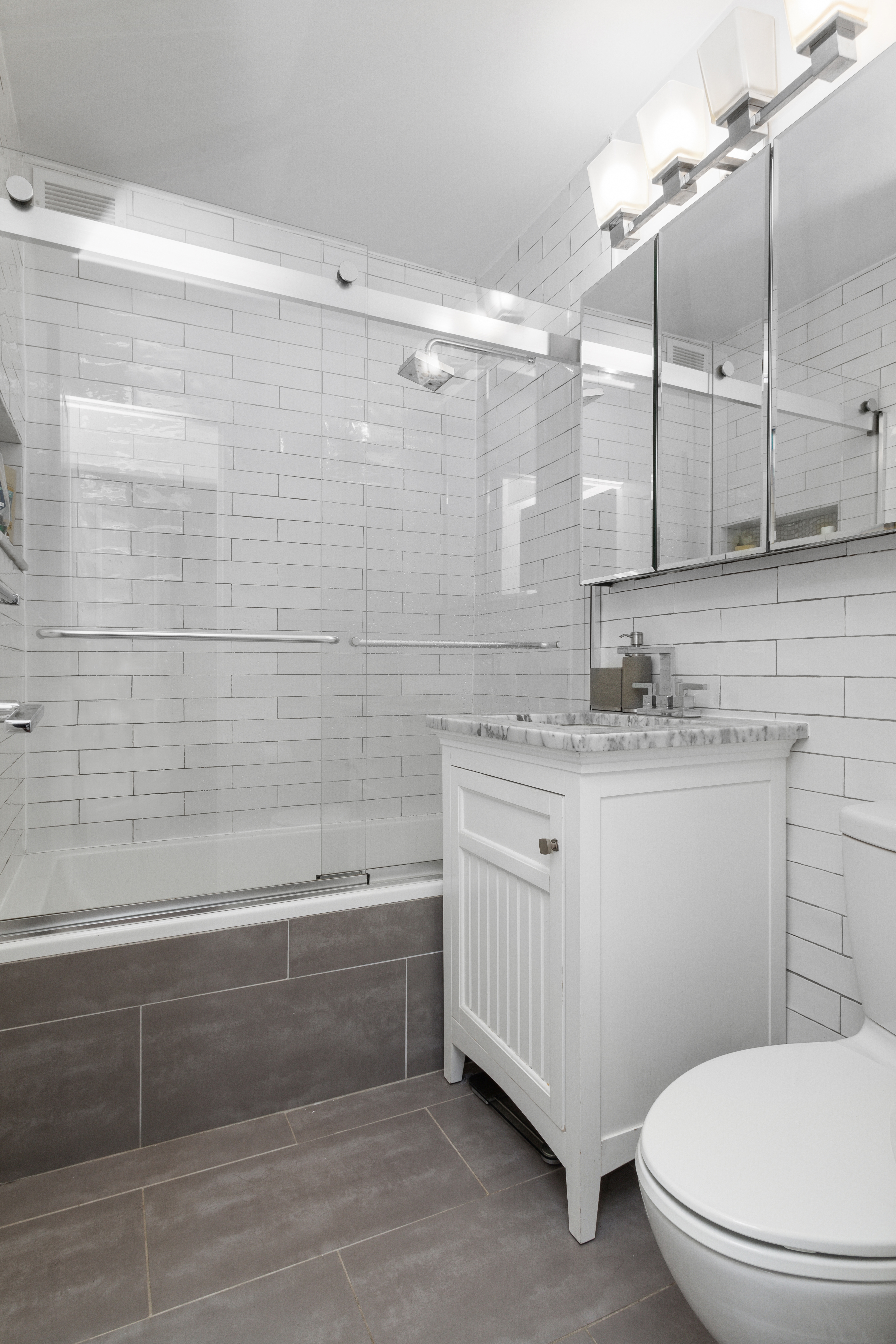 400 East 54th Street, Unit 7D Manhattan, NY 10022 - Photo 5 of 6 a bathroom with a granite countertop sink a toilet a mirror and bathtub
