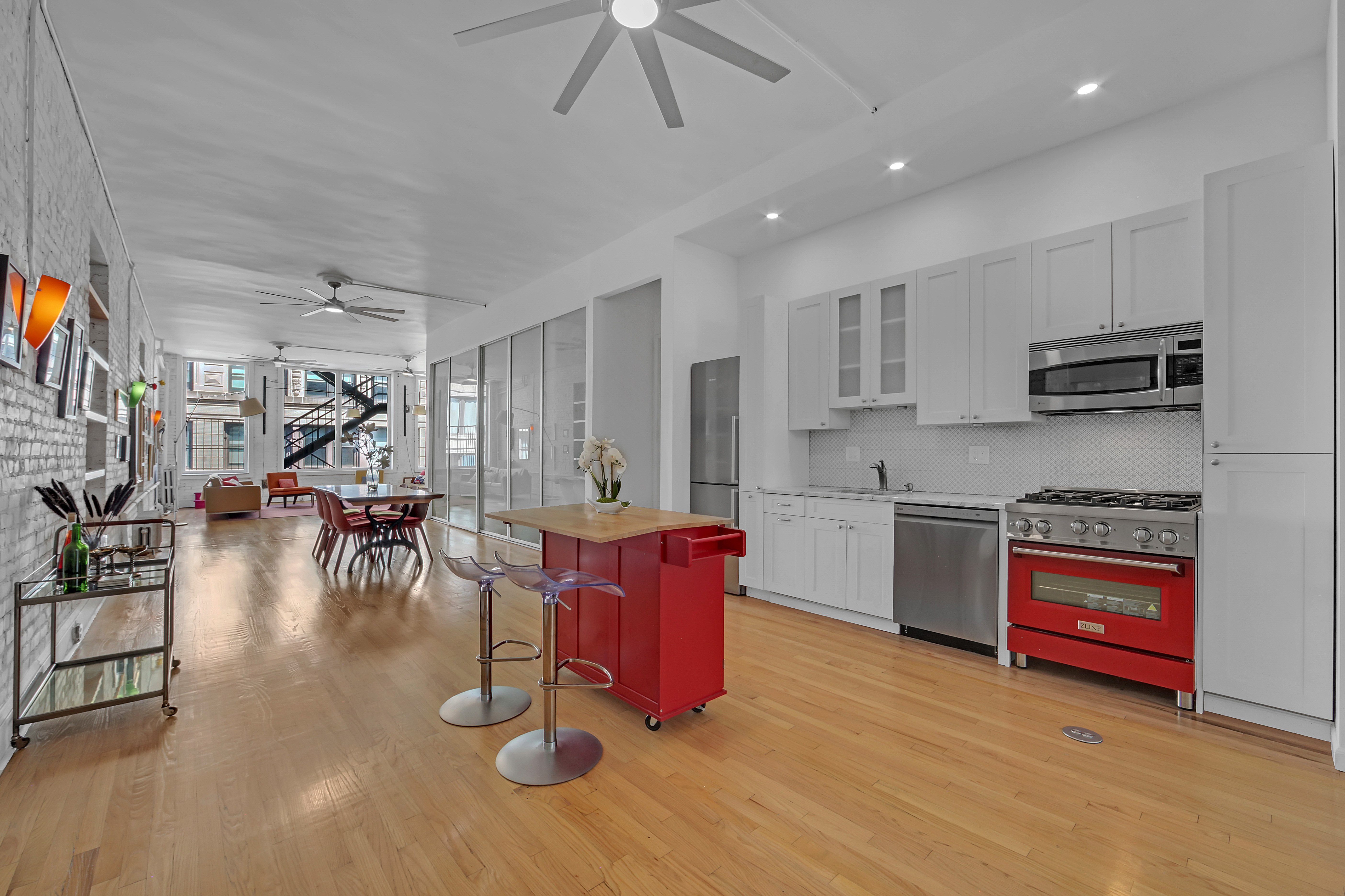 56 East 11th Street, Unit 7 Manhattan, NY 10003 - Photo 6 of 16 a kitchen with stainless steel appliances kitchen island granite countertop a stove a refrigerator a sink a stove with island and chairs