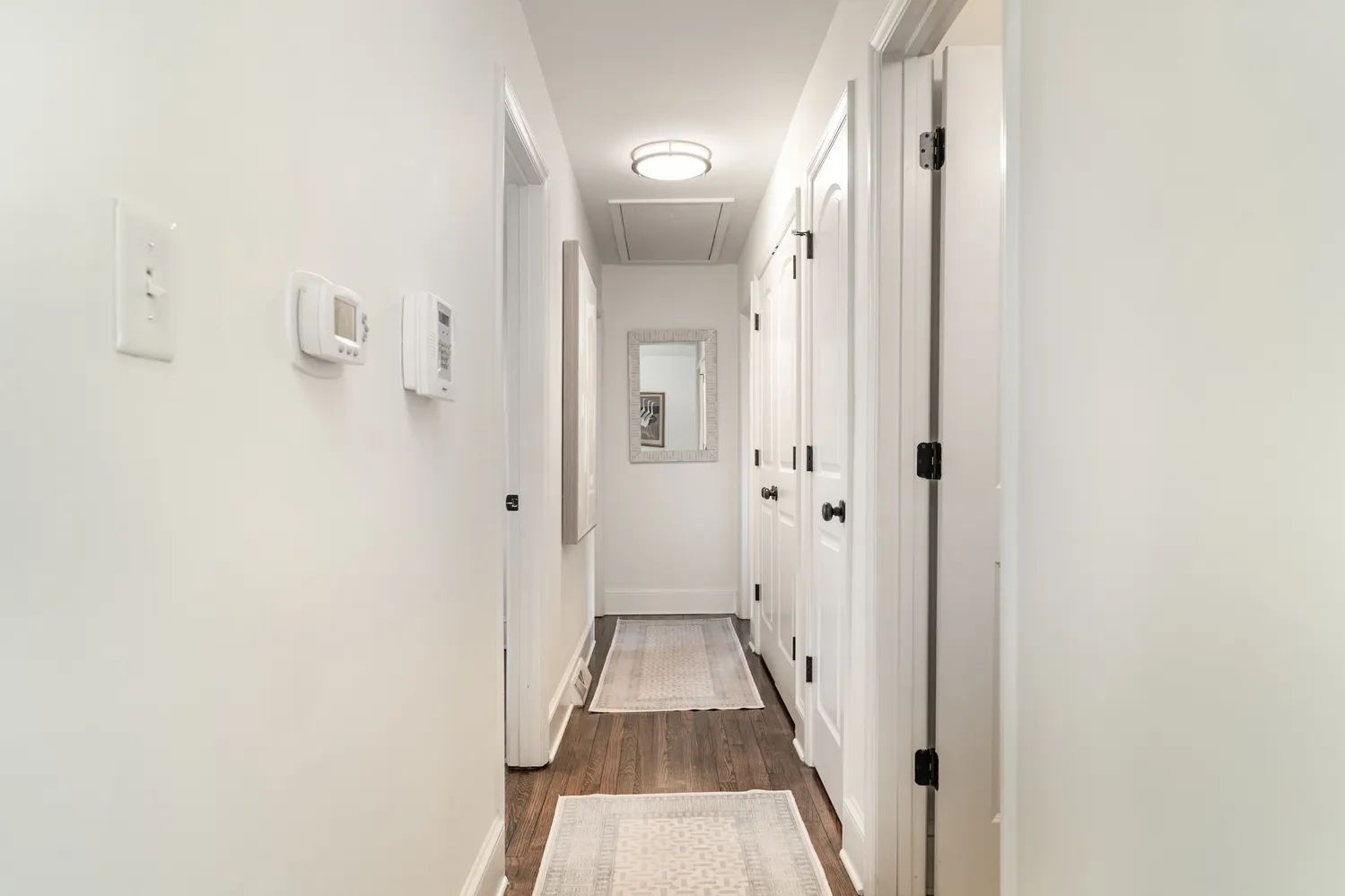 a view of a hallway with wooden floor and a bathroom