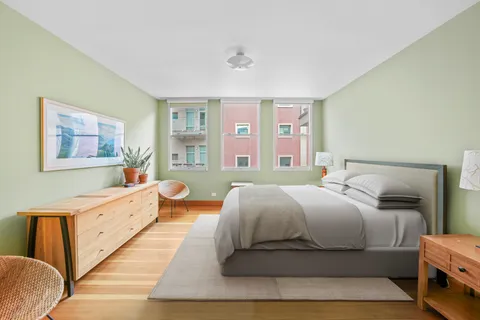 a bedroom with a bed and a dresser next to a window