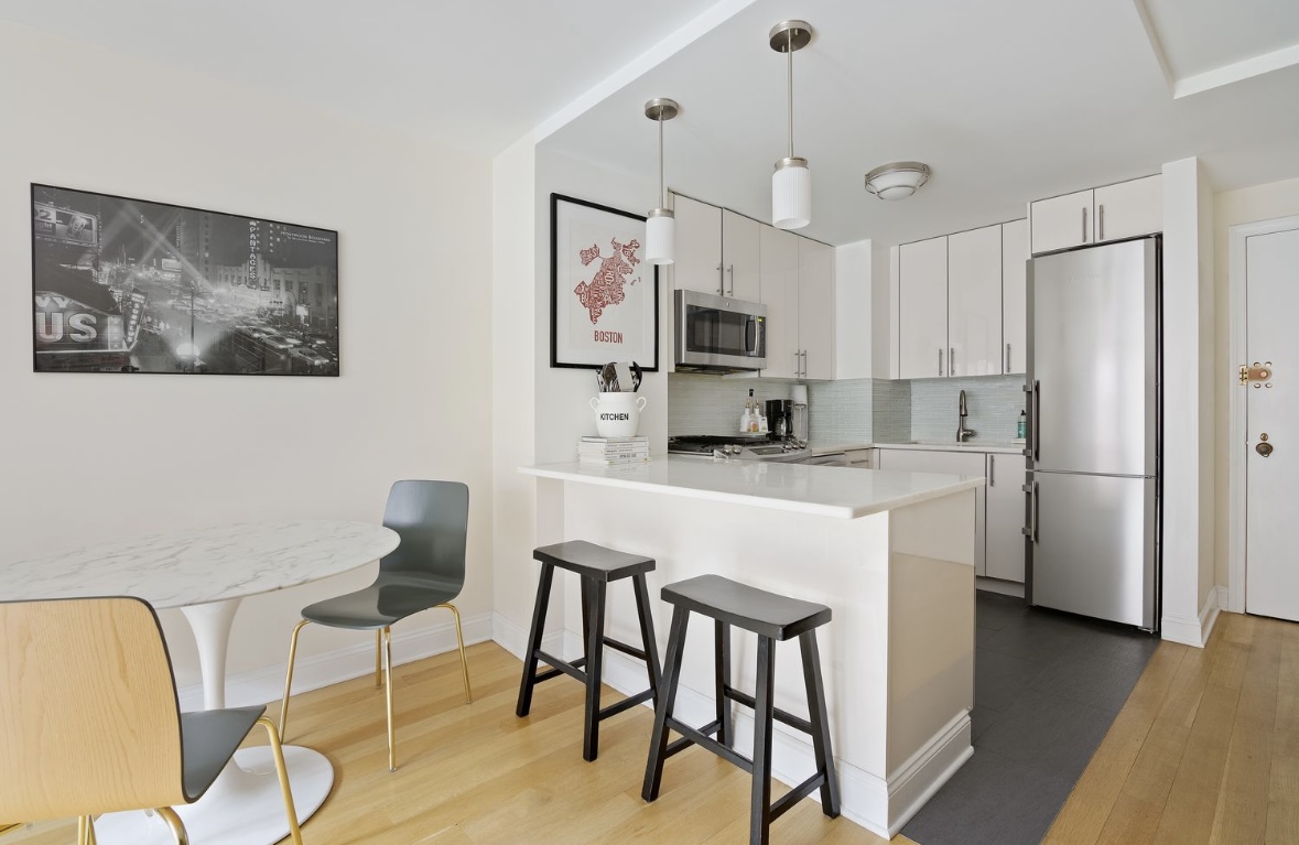 201 East 25th Street, Unit 4C Manhattan, NY 10010 - Photo 2 of 6 a kitchen with kitchen island a stove a table and chairs in it