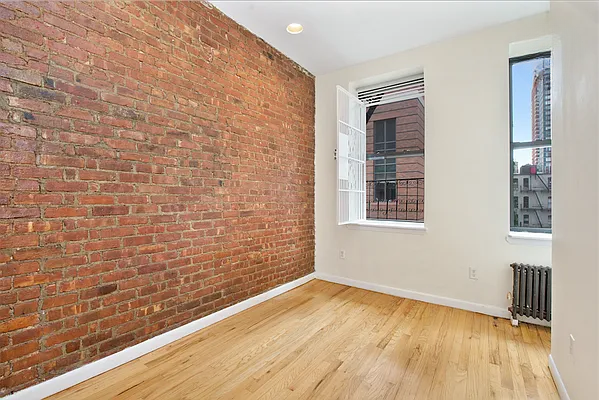 309 East 95th Street, Unit 23 Manhattan, NY 10128 - Photo 5 of 6 a view of an empty room with wooden floor and a window
