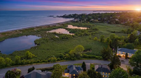 an aerial view of a city with lots of residential buildings ocean and mountain view in back